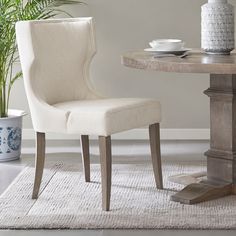 a dining room with a table and chair next to a potted plant on the floor