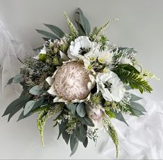 an arrangement of flowers and greenery on a white background