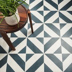 a potted plant sitting on top of a wooden table next to a black and white tiled floor