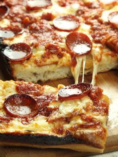 a pizza with pepperoni and cheese is being cut into slices on a cutting board