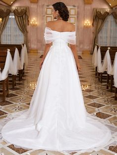 a woman in a white wedding dress looking down at the floor with chairs around her