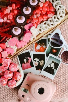 a pink polaroid camera sitting on top of a table next to pictures and candies