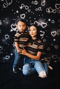 a mother and son posing for a photo in front of hearts on a black background