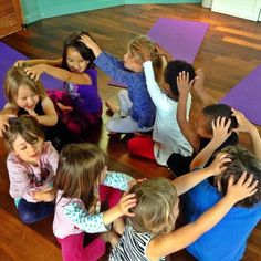 a group of children standing in a circle on yoga mats with their arms around each other