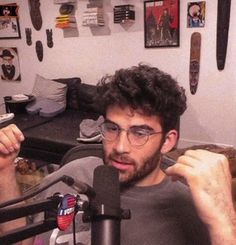 a man sitting in front of a microphone with his hand up to the camera and another person standing next to him