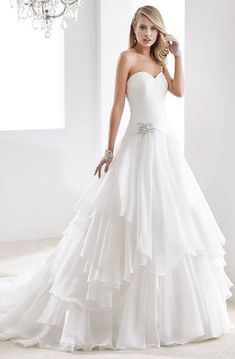 a woman in a white wedding dress standing next to a chandelier