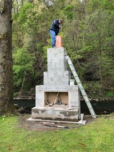 a man standing on top of a cement block structure next to a river in the woods