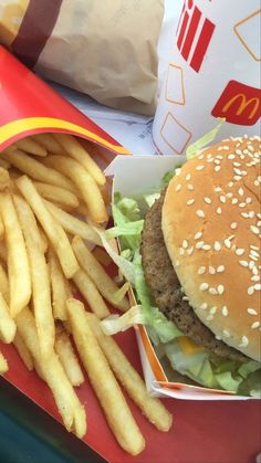 a hamburger and french fries on a red tray with a bag of mcdonald's