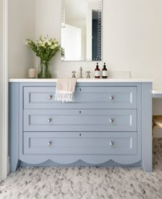 a bathroom with a blue vanity and white counter tops, along with a mirror on the wall