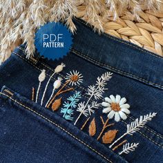 a pair of jeans with embroidered daisies on the back pocket and side seams