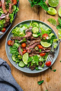 a steak salad with tomatoes, cucumbers and lettuce on a plate