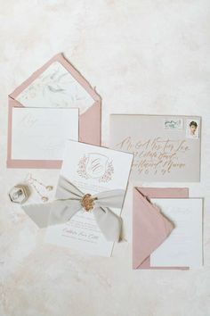 the wedding stationery is laid out on top of each other, including pink and white envelopes