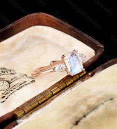 an engagement ring in a wooden box on top of a piece of paper with writing