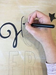 a person is writing the word friday on a piece of plywood with black marker