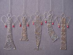 four metal ornaments hanging from strings with red beads and wire on the end of each ornament