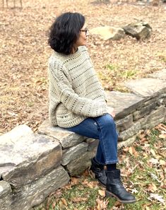 a woman sitting on top of a stone wall