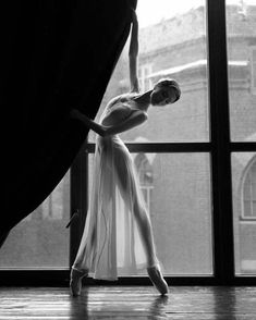 a ballerina standing in front of a window