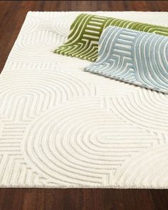 three different colored pillows sitting on top of a wooden floor next to a white rug