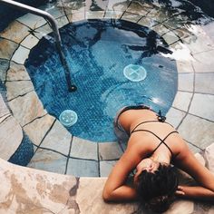 a woman laying on the ground next to a swimming pool