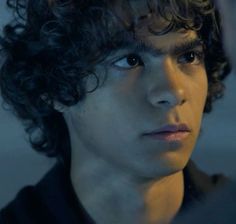 a young man with curly hair looking at the camera