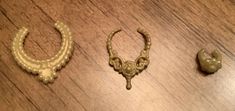 three pieces of jewelry sitting on top of a wooden table next to an earring