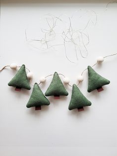 four felt christmas trees are hanging from string