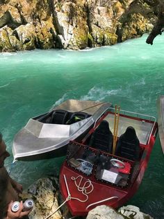 two small boats in the water next to some rocks