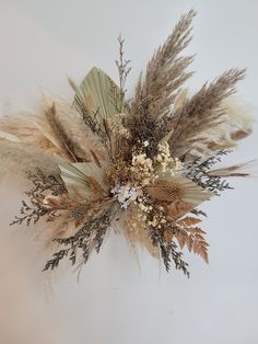 an arrangement of dried flowers and leaves on a white background