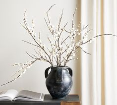 a vase filled with white flowers sitting on top of a table next to an open book