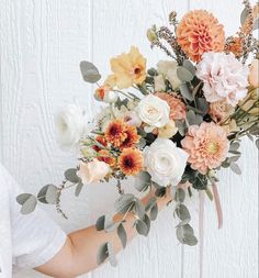 a person holding a bouquet of flowers in their hand with white background and wood planks