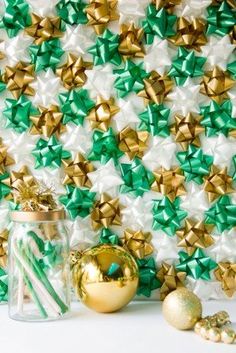 a glass jar filled with candy canes next to gold and green christmas decorations on a white surface