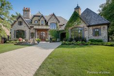 a large brick house with lots of windows and landscaping on the front lawn, surrounded by lush green grass