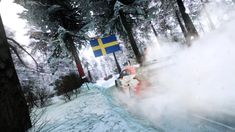 a person riding a snowmobile on a snowy road in front of trees and a swedish flag