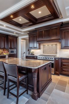 a large kitchen with wooden cabinets and marble counter tops, along with two bar stools