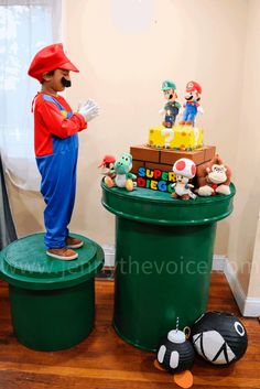 a statue of mario is standing on top of a trash can with toys around it