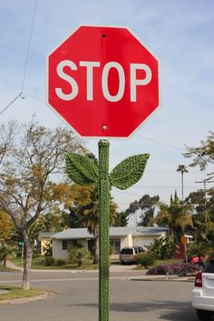 a red stop sign sitting on the side of a road next to a white car