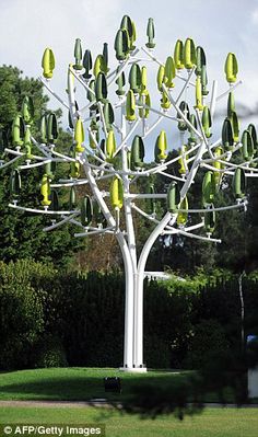 a large metal tree with green leaves on it's branches in a park setting