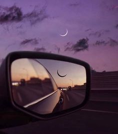 a car's side view mirror with the moon in the sky