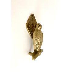 a gold owl brooch sitting on top of a white wall