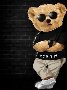 a brown teddy bear wearing sunglasses standing in front of a brick wall with his arms crossed