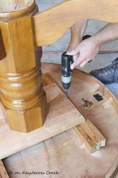 a person using a drill to attach a piece of wood on top of a table