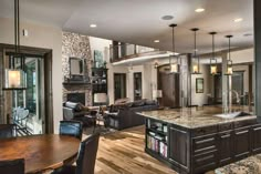 a large kitchen and living room with wood flooring in the center, open concept