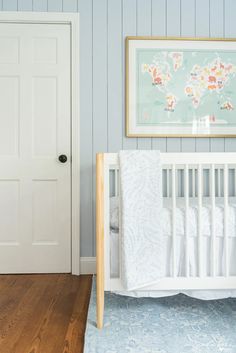 a white crib in a blue and white nursery with a world map on the wall