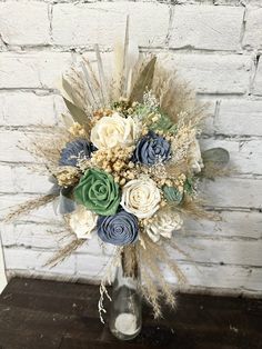 a vase filled with lots of flowers on top of a wooden table next to a brick wall