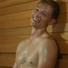 a shirtless man is smiling while in the sauna