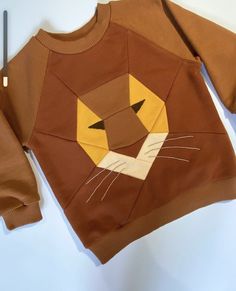 a brown sweater with a lion face on the front, and a cat's head on the back