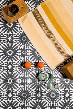 the table is covered with an orange and white place mat, scissors, coffee cup, and other items