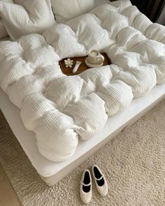 a bed that has been made into a couch with pillows on it and a cup of coffee in the middle