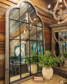 a mirror sitting on top of a wooden table next to a vase filled with plants