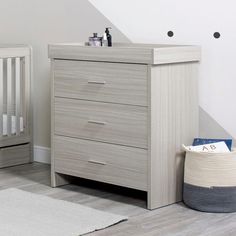 a baby crib next to a dresser in a room